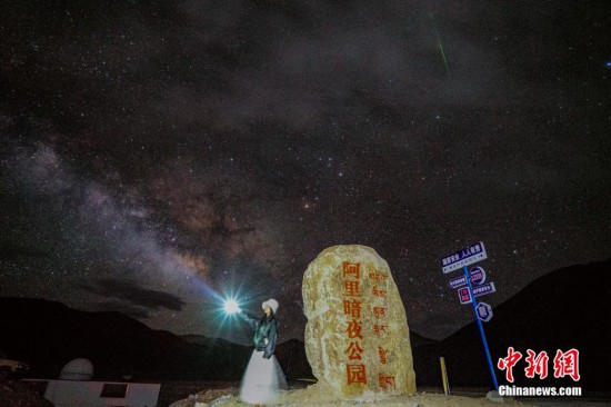 图为6月20日晚，游客“打卡”西藏阿里暗夜公园，天上是银河与流星（右上角）。曹枝清 摄