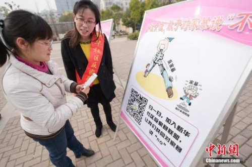 资料图：今年3月8日，安徽合肥新华社区志愿者夏一琼(右)向市民普及反家暴相关法律知识。钟欣 摄